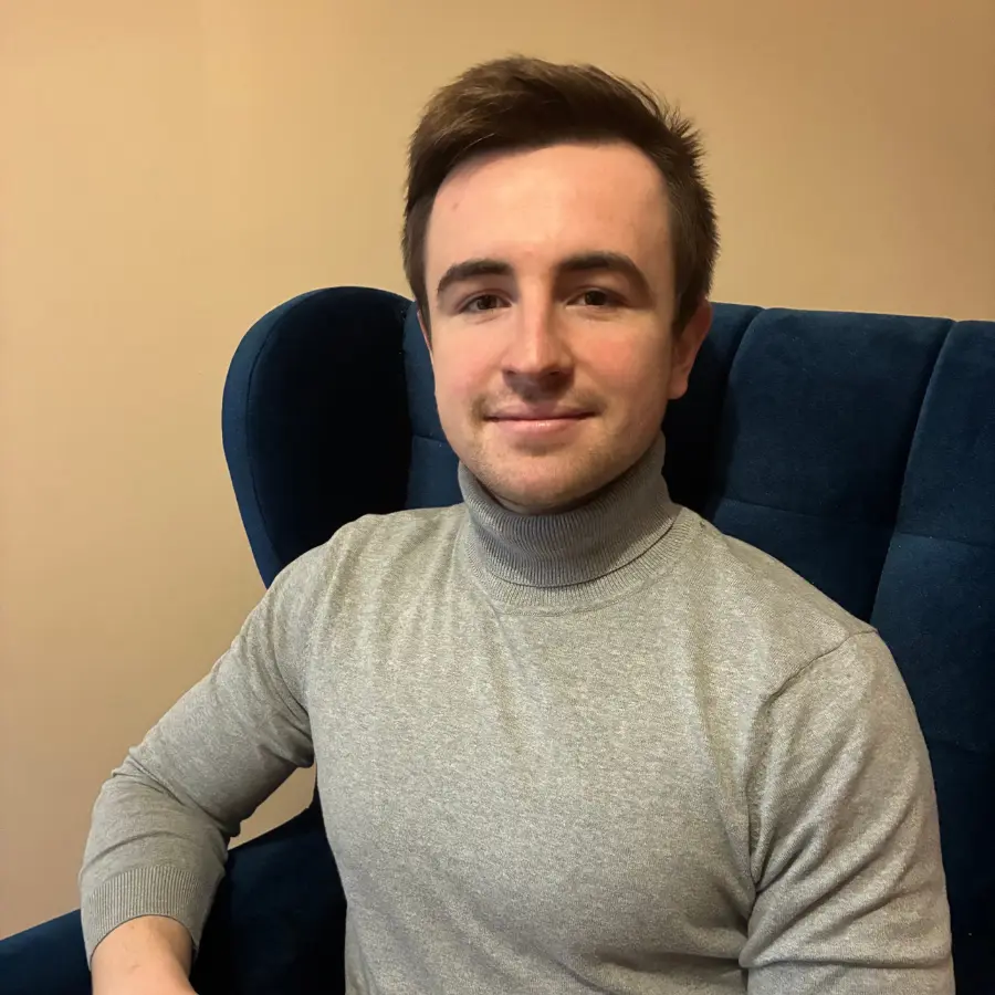 Przemysław Szyller - psycholog Labiryntu Myśli w Szczecinie siedzi na granatowym fotelu